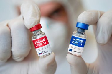 İki şişe Cavid 19 Coronavirus aşısı ve beyaz masada bir şırınga. Covid-19 salgınıyla mücadelenin tıbbi konsepti.