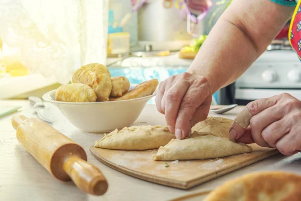 Бабушка готовит пироги. Домашняя еда. домашние торты из теста в женских руках. Процесс приготовления пирога тесто вручную — стоковое фото