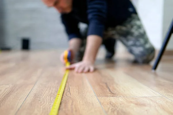 Worker guy measures the length of the room. Focus on the ruler. The man is out of focus. — Stock Photo, Image