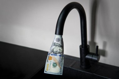 İçinden dolar akan bir musluk. Pahalı su kaynağı. Nüfus için kamu hizmetlerinin fiyatını artırma kavramı. Evde pahalı sıcak ve soğuk su var..