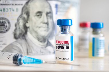 Covid-19 Coronavirus enfeksiyon aşısı ve masanın üzerinde paranın arka planına karşı bir şırınga. Yüksek maliyetli aşı üretimi kavramı.