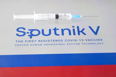 Koronovirüs enfeksiyonundan elde edilen Sputnik V aşısı covid-19 ve arka plan Rus bayrağında bir şırınga. 18 Ocak 2021, Barnaul, Rusya.