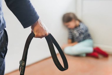 The girl is sitting in the corner hiding from her abusive stepfather. The concept of raising children through domestic violence. Punishment for a crime with a belt. The problem of child abuse. clipart