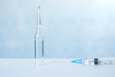 Bir şişe sıvı, bir aşı ve mavi arka planda tıbbi bir şırınga. Koronavirüse karşı aşı kavramı. Banner, boşluğu kopyala.