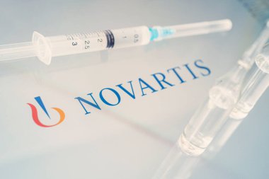 Beyaz bir masada sıvı şişeleri ve büyük bir ilaç şirketi olan Novartis 'in logosu. 15 Mart, Barnaul, Rusya.