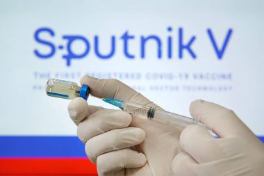 Bir doktor, Sputnik V logosunun arka planında Coronavirus covid 19 'a karşı aşı hazırlıyor. 18 Ocak 2021, Barnaul, Rusya.