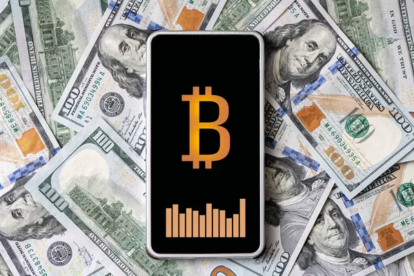 concept of earning money on cryptocurrency. A smartphone with a bitcoin logo and a currency exchange rate chart on the smartphone screen against the background of money. All the graphics are made up.