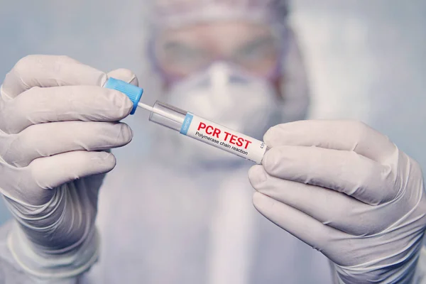 PCR testi. Coronavirus COVID19 test kiti teçhizatı tutan sağlık uzmanı, hasta örnek inceleme analizi, tehlikeli madde koruma giysisi içinde laboratuar bilim adamı steril DNA örneği tüpünü denetliyor.