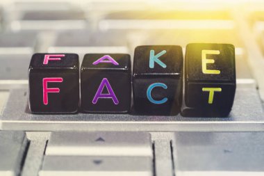 Siyah küpler gri dizüstü bilgisayar klavyesinde kelimeleri sahtesinden gerçeğe çevirirler. Gerçeklerle oynama kavramı. İnternetten sahte haberler. Sahte haberler