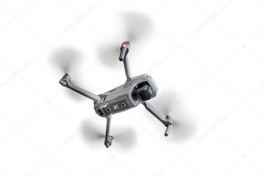 A flying quadcopter is isolated on a blue background.