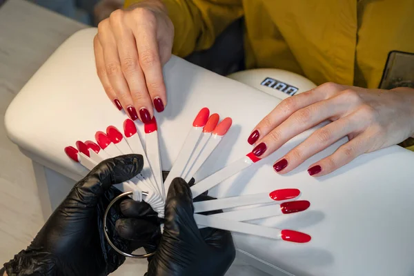 Gel polish. Nail polish in different colors. Woman at nail studio chosing color of nail polish.