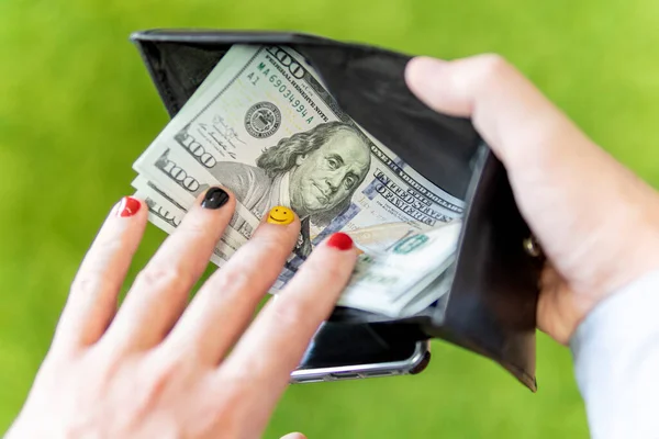 Man gets money from the wallet. The guy recalculates the salary on a green background. Beautiful design of men's nails.
