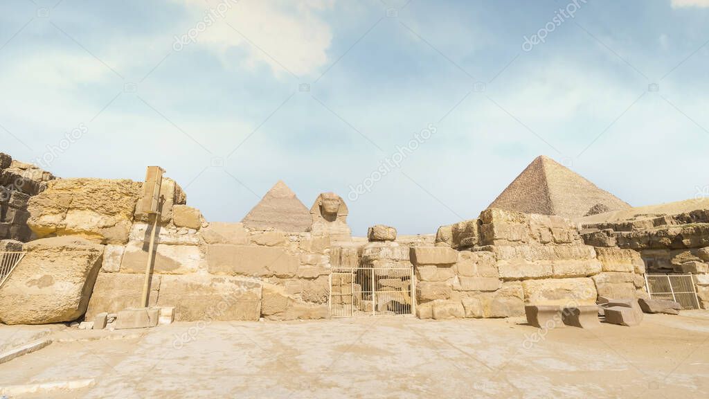 Great Sphinx with pyramid in the background on a beautiful blue sky day in Giza, Cairo, Egypt.