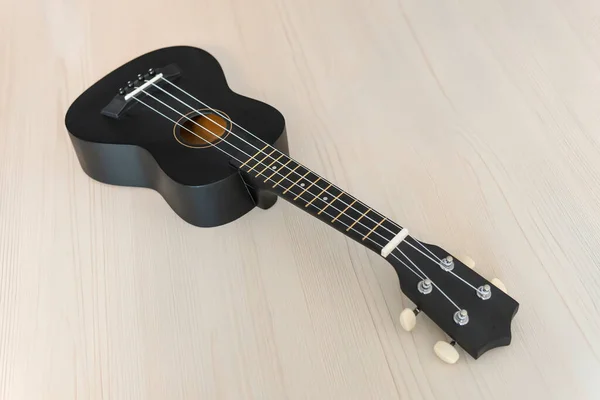 Guitar on textured wood. Acoustic guitar on wooden table with text space. Instrument of folk music. classic black concert ukulele