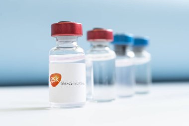 Vials of liquid on a white table and the logo GlaxoSmithKline, large pharmaceutical company. March 15, 2021. Barnaul, Russia.