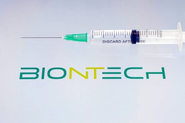 Vials of liquid on a white table and the logo biontech, large pharmaceutical company. March 15, 2021. Barnaul, Russia.