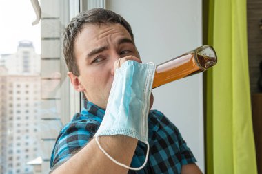 Alkolizm, alkol bağımlılığı ve evde rom şişesi olan erkek alkolik kavramı. Sıkıntıdan tek başına sarhoş olan işsiz bir uzman kendini izole ederek karantinaya alındı..