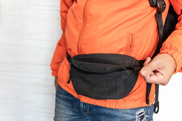 A black waist bag on the traveler\'s stomach. Comfortable Fashionable Travel Belt Bag