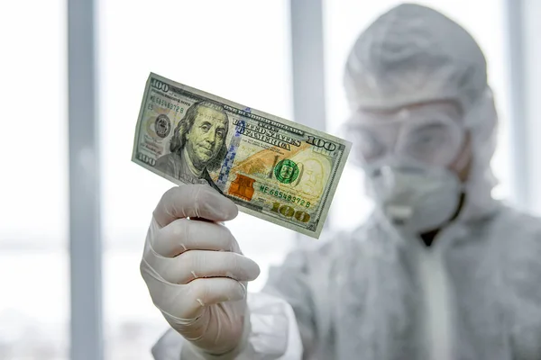 doctor in a protective mask and a virus-proof suit in the hospital counts money. Payment to Employees in the red zone. A dangerous job with a low salary. Award to doctors working with covid patients