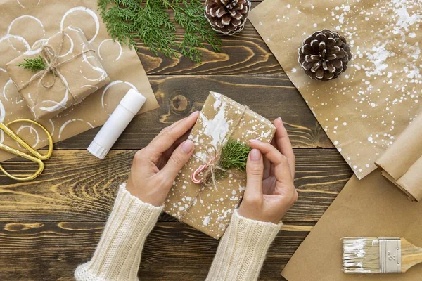 Üst görüşlü eller, çam kozalaklarıyla Noel hediyesini tutuyorlar. Çözünürlük ve yüksek kaliteli güzel fotoğraf