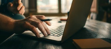 Dizüstü bilgisayarlı erkek ellerinin yakın plan fotoğrafı. Adam evden uzak bir yerde çalışıyor. Serbest İşçi