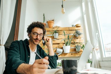 Bilgisayarı ve akıllı telefonu olan yakışıklı bir adam evden uzakta çalışıyor. Uzaktan kumandada serbest çalışan biri. Rahat iş yeri