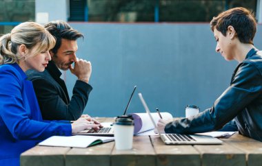 Açık havada birlikte çalışan bir grup iş arkadaşı. Modern iş adamları kahve molası sırasında tartışıyorlar..