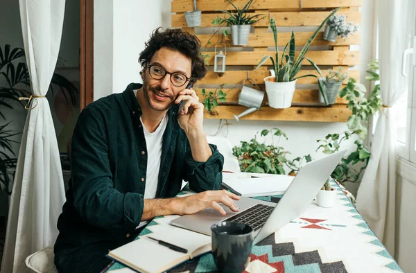 Handsome man with laptop and smartphone working remotely from home. Freelancer at remote work. Cozy workplace