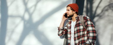 Sokakta akıllı telefonu olan modern bir gencin portresi. Elinde cep telefonu olan hippi bir adam.