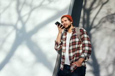 Sokakta akıllı telefonu olan modern bir gencin portresi. Elinde cep telefonu olan hippi bir adam. Sesli mesaj kaydediliyor