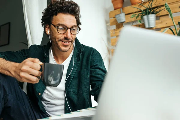 Handsome man with laptop working remotely from home, making video call. Freelancer at remote work. Cozy workplace