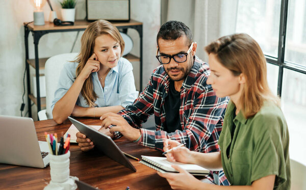 Группа молодых людей, работающих вместе. Творческие бизнесмены в современном офисе. Команда хипстеров в коворкинге. Молодые современные коллеги. Командная работа.