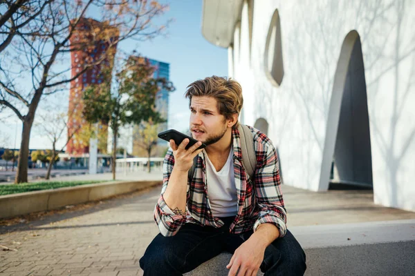 Sokakta akıllı telefonu olan modern bir gencin portresi. Elinde cep telefonu olan hippi bir adam. Sesli mesaj kaydediliyor