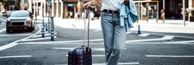 Güneşli bir caddede valizli genç bir kadın. Gezgin tatilde. Taksi bekliyorum.