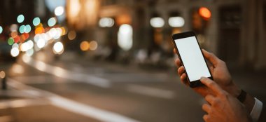 Gece sokağında elinde akıllı telefon olan erkeklerin yakın plan fotoğrafı. Boş ekran. Model