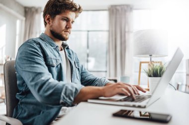 Dizüstü bilgisayarda yazan genç adam. Güneşli ofisteki modern iş adamı. İşyerinde serbest çalışan biri. Blogcu ya da gazeteci yeni makale yazıyor