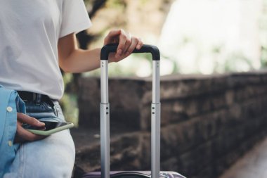 Bavulu tutan bir kadının yakın plan fotoğrafı. Şehir caddesinde bagajı olan genç bir kadın. Gezgin tatilde..