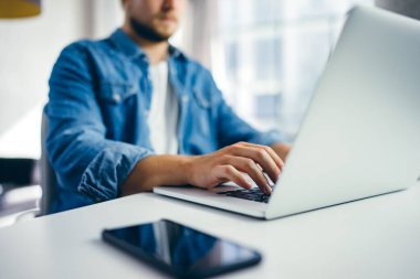 Dizüstü bilgisayarda yazan genç adam. Güneşli ofisteki modern iş adamı. İşyerinde serbest çalışan biri. Blogcu ya da gazeteci yeni makale yazıyor