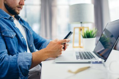 Akıllı telefonu elinde daktilo eden genç bir adam. Güneşli ofisteki modern iş adamı. Serbest İşçi.