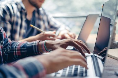 Birlikte çalışan bir grup genç. Modern ofiste yaratıcı iş adamları. Hippi takımı birlikte çalışıyor. İş arkadaşları işte. Erkek ellerinin dizüstü bilgisayarla yakın plan görüntüleri.