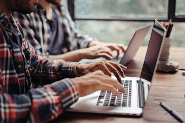 Birlikte çalışan bir grup genç. Modern ofiste yaratıcı iş adamları. Hippi takımı birlikte çalışıyor. Bağımsızlar iş başında. Erkek ellerinin dizüstü bilgisayarla yakın plan görüntüleri..