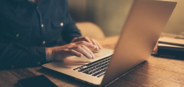 Dizüstü bilgisayarlı erkek ellerinin yakın plan fotoğrafı. İnsanlar evlerinde uzaktan çalışıyor. Uzaklık işi