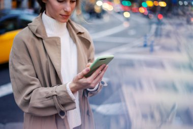 Gece sokakta akıllı telefon kullanan genç bir kadın.