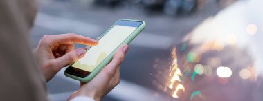 Modern akıllı telefonu boş ekranla tutan kadınların yakın plan görüntüleri. Model mesaj ya da içerik için hazır. Cep telefonlu bir kadın eli. Boş ekran. Gece Caddesi, Bokeh Light