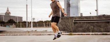 Kaslı genç adam dışarıda ip atlamakla egzersiz yapıyor.