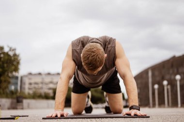 Genç atletik adam antrenman yapıyor. Spor salonu açık havada. Şınav. Şehir arkaplanı.