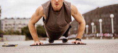 Genç atletik adam antrenman yapıyor. Spor salonu açık havada. Şınav. Şehir arkaplanı.