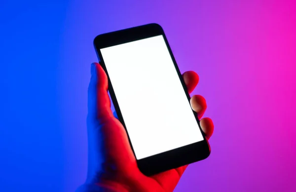 Akıllı telefonlu bir erkek. Boş beyaz ekran. Model-up. Kırmızı ve mavi neon ışık.