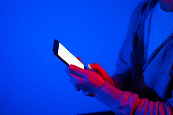 Male hand with smartphone. Blank white screen. Mock-up. Red and blue neon light.