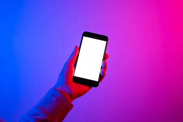 Akıllı telefonlu bir erkek. Boş beyaz ekran. Model-up. Kırmızı ve mavi neon ışık.